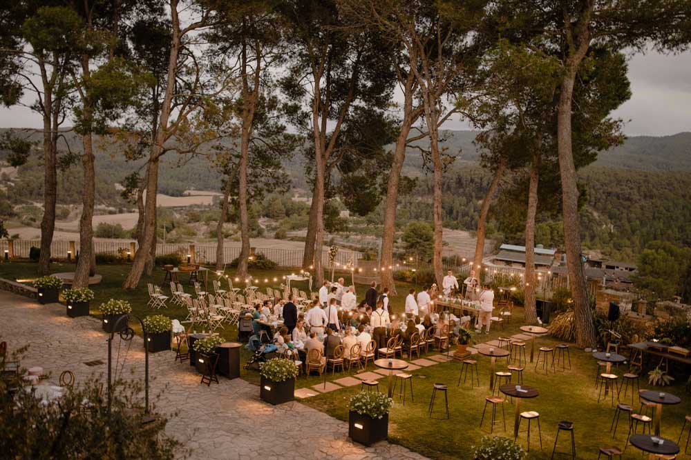 Guirnaldas de luces cálidas iluminando mesas en una boda al aire libre de noche con ambiente romántico.